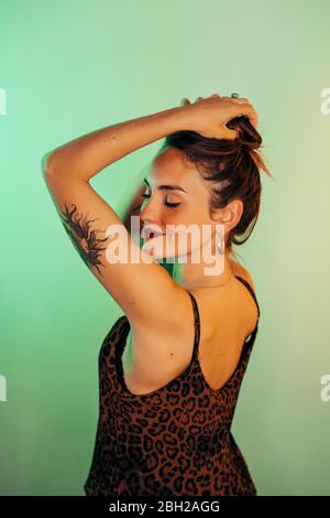 Portrait of tattooed young woman with eyes closed against green background Stock Photo