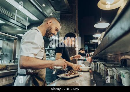 chefs in restaurant arranging food on plates for serving Stock Photo