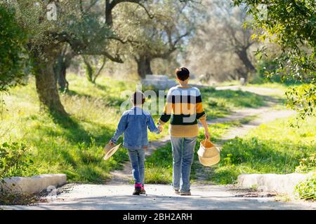 Mother and daughter walking hand in hand on a rural path Stock Photo