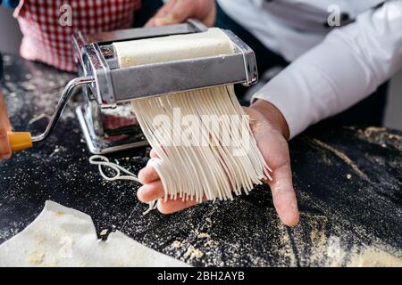 Making homemade pasta with pasta machine in kitchen at home Stock Photo
