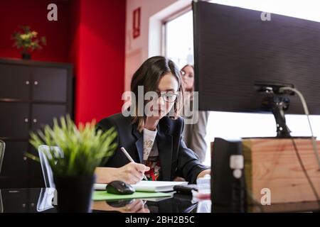 Young businesswoman taking notes at desk in office Stock Photo