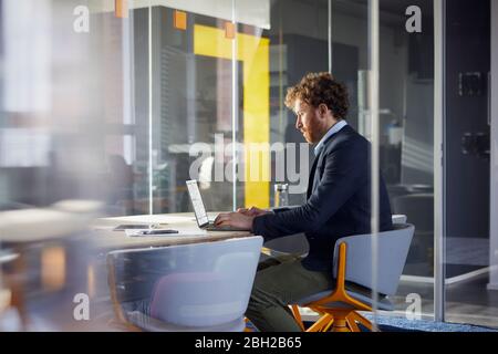 Businessman sitting at desk in office using laptop Stock Photo