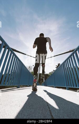 Rear view of disabled athlete with leg prosthesis running on a bridge Stock Photo