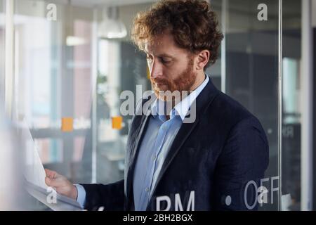 Portrait of businessman reading papers in office Stock Photo