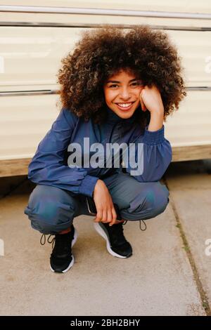 Portrait of happy stylish young woman wearing tracksuit outdoors Stock Photo