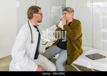 Doctor comforting sad senior patient in medical practice Stock Photo