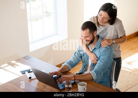 Happy young couple using laptop at home Stock Photo