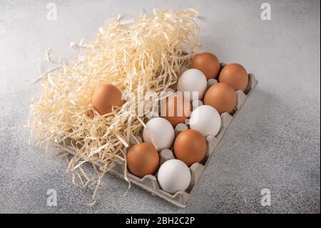 Brown and white chicken eggs in a eco-friendly package from paper and straw on light textured background Stock Photo