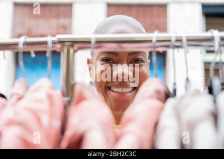 Portrait of happy woman behind clothes rail Stock Photo
