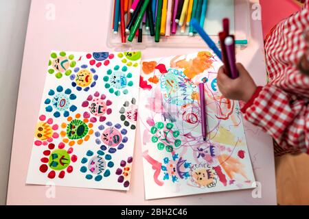 Little girl drawing  ugly viruses with color markers at home Stock Photo