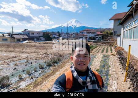A tourist man is taking a selfie while walking on the road of Yamanashi city to see the great Chureito Pagoda. Yamanashi, Japan February 9,2020 Stock Photo