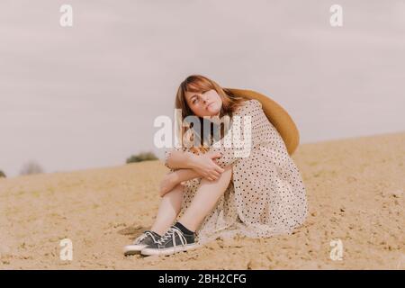 Portrait of woman in vintage dress sitting on a remote field in the countryside