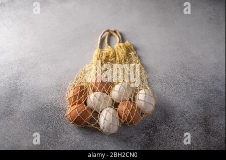 Brown and white chicken eggs in string bag on a light textured background. Copy space Stock Photo