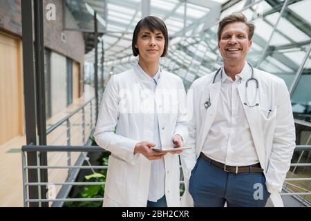 Two doctors standing in atrium, holding digital tablet Stock Photo