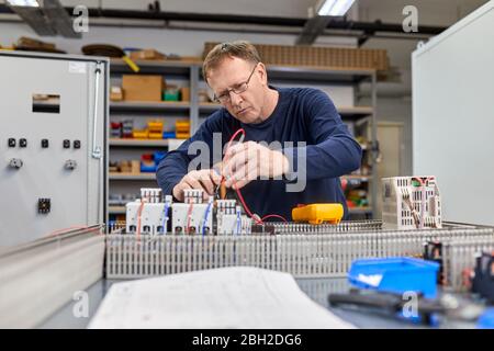 Electrician working on circuitry in workshop Stock Photo