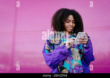Young woman typing on smartphone and listening to music Stock Photo