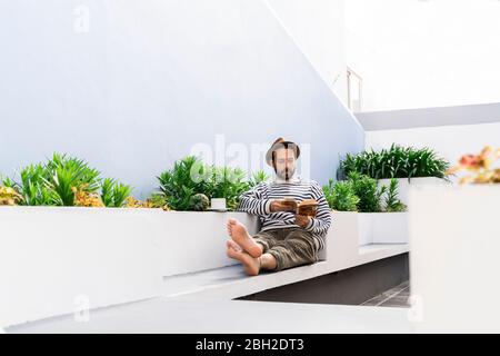 Man sitting on balcony reading a book Stock Photo