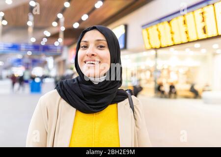 Portrait of smiling young woman wearing hijab at train station Stock Photo