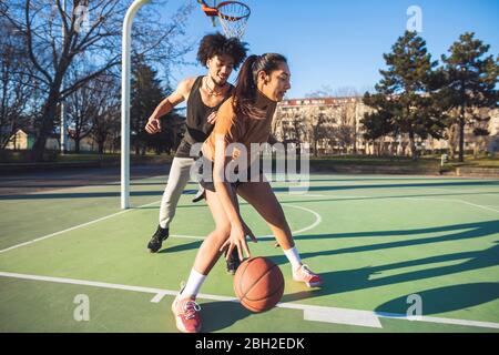 Young man and woman playing basketball on court Stock Photo