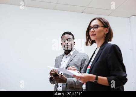 Two colleagues with cell phone and paper in office Stock Photo