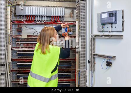 Female electrician working with voltmeter at fuse box Stock Photo