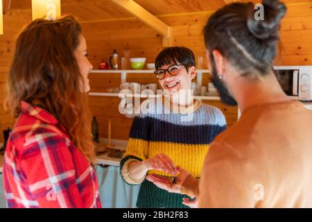 Host welcoming young couple in a cabin in the countryside handing over house key Stock Photo