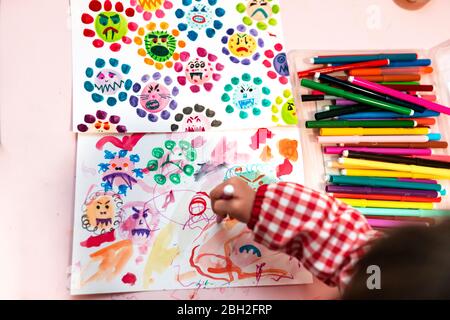 Little girl drawing  ugly viruses with color markers at home Stock Photo