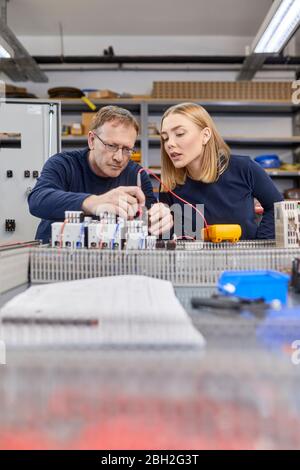 Two electricians working on circuitry in workshop Stock Photo