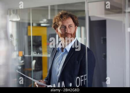 Portrait of confident businessman holding papers in office Stock Photo