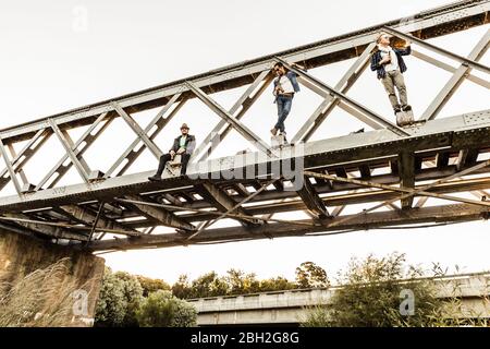 Three men with beer bottles on an old railway bridge Stock Photo