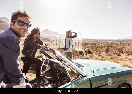 Happy friends on a road trip with convertible car