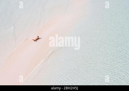 Woman sunbathung on white sand bank in the sea, Bahamas, Carribean Stock Photo