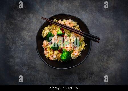 Bowl of fried basmati rice with broccoli, shrimps, chili, cilantro, lime and ginger Stock Photo