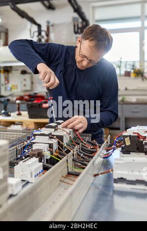Electrician working on circuitry in workshop Stock Photo