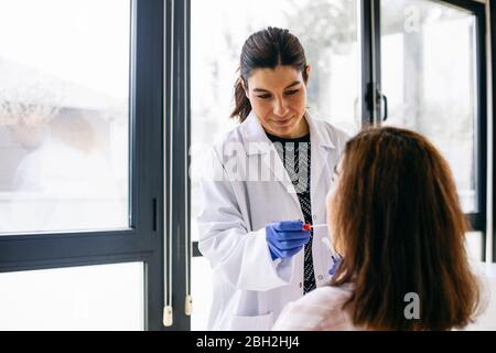 Doctor taking swab from the patient's mouth Stock Photo
