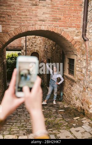 Woman taking a picture of her friend in picturesque old town, Greve in Chianti, Tuscany, Italy Stock Photo