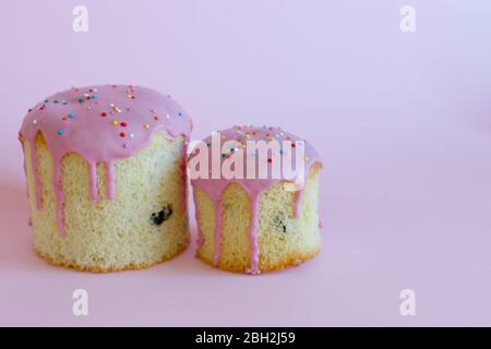 Sweet bread traditional easter orthodox celebration cake panettone also called kulich glazed with pink icing and raisins on pink background Stock Photo