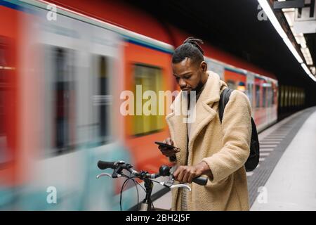 Stylish man with a bicycle and smartphone in a metro station Stock Photo