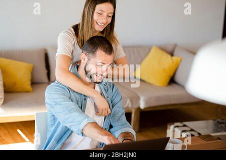 Happy young couple using laptop at home Stock Photo