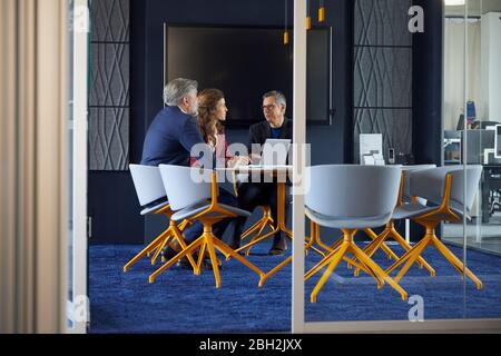 Two businessmen and businesswoman working together on a project in office Stock Photo