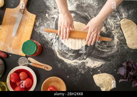 Woman's hands rolling out dough on worktop Stock Photo