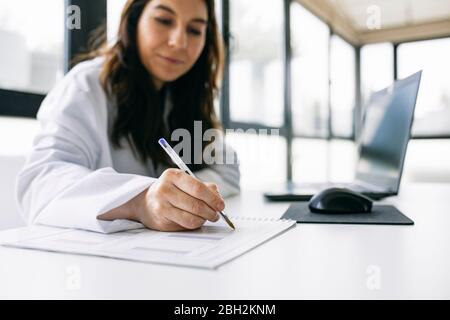Doctor sitting at desk in medical practice taking notes Stock Photo