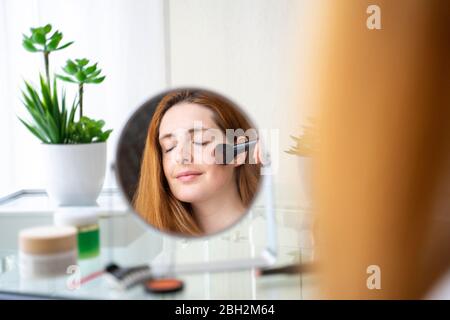 Young woman applying make up at home Stock Photo