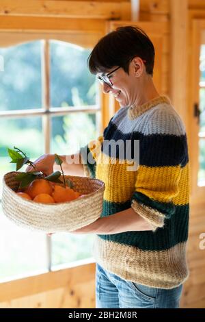 Woman with basket of oranges in a wooden cabin Stock Photo