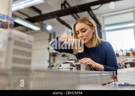 Female electrician working on circuitry in workshop Stock Photo
