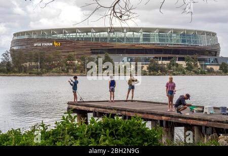 Father and children fishing off a wooden jetty on the Swan River and Optus Stadium Perth Western Australia. Stock Photo