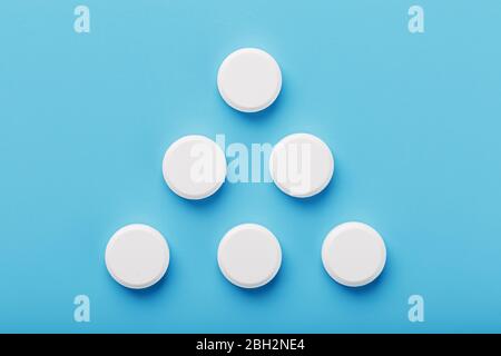 Round medicinal tablets in the shape of a triangle on a blue background ...