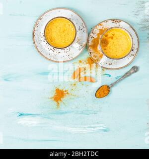 Turmeric curcuma golden milk drink with spices on blue background Stock Photo