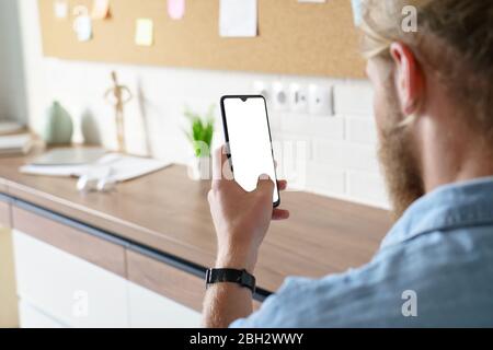 Man using smart phone mock up white screen, over shoulder view. Stock Photo