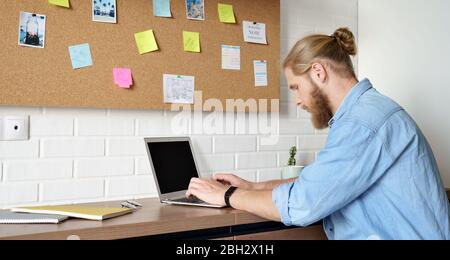 Serious man using laptop working or studying from home sitting at office desk. Stock Photo